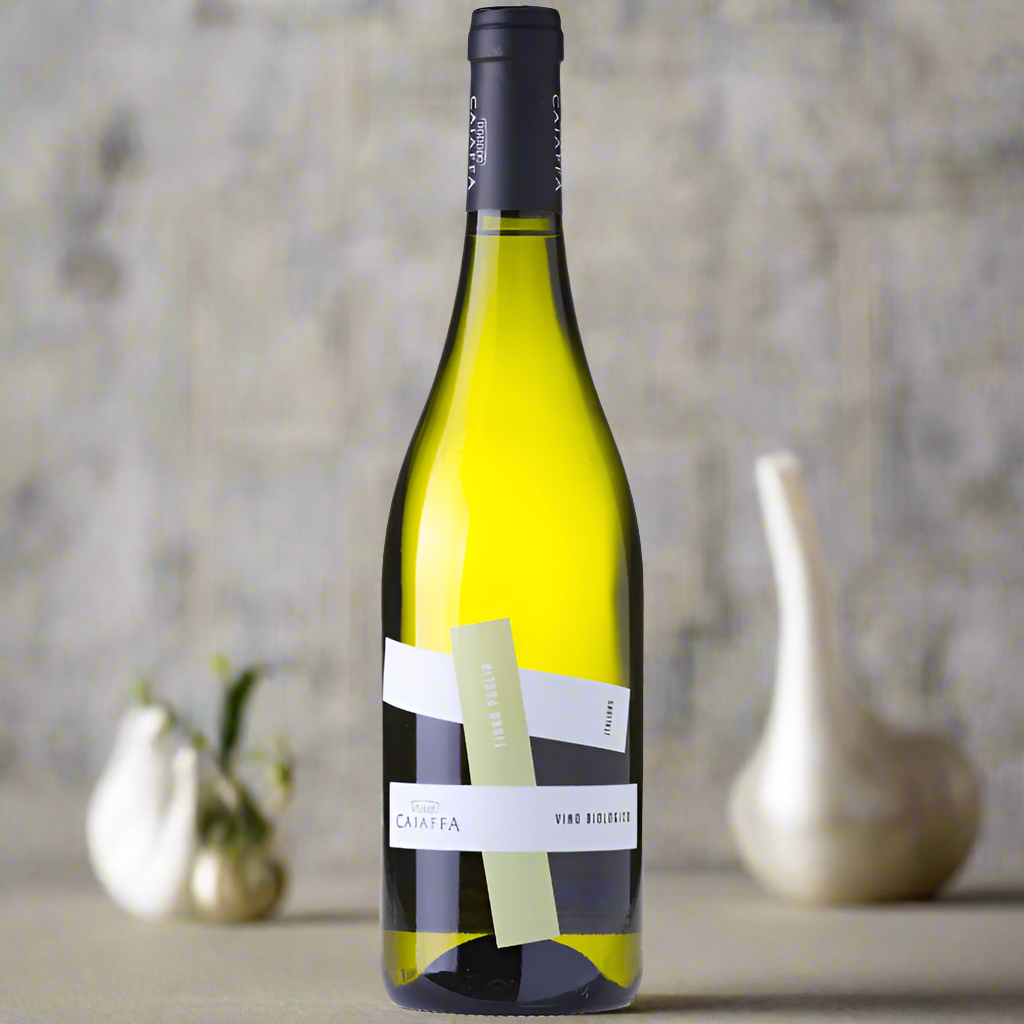 Place a bottle of Caiaffa Fiano on a sleek dining table with fresh seafood dishes, white linens, and soft natural light creating a chic, relaxed atmosphere.