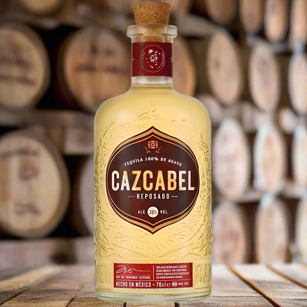 Cazcabel Tequila Reposado bottle displayed on a wooden barrel in a rustic tequila ageing room