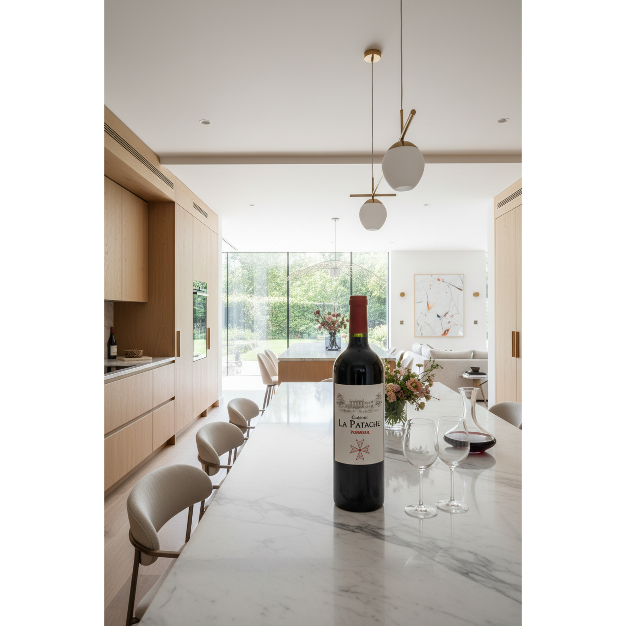 Chateau La Patache Pomerol wine bottle displayed on a polished stone dining table in a bright contemporary kitchen and entertaining space.