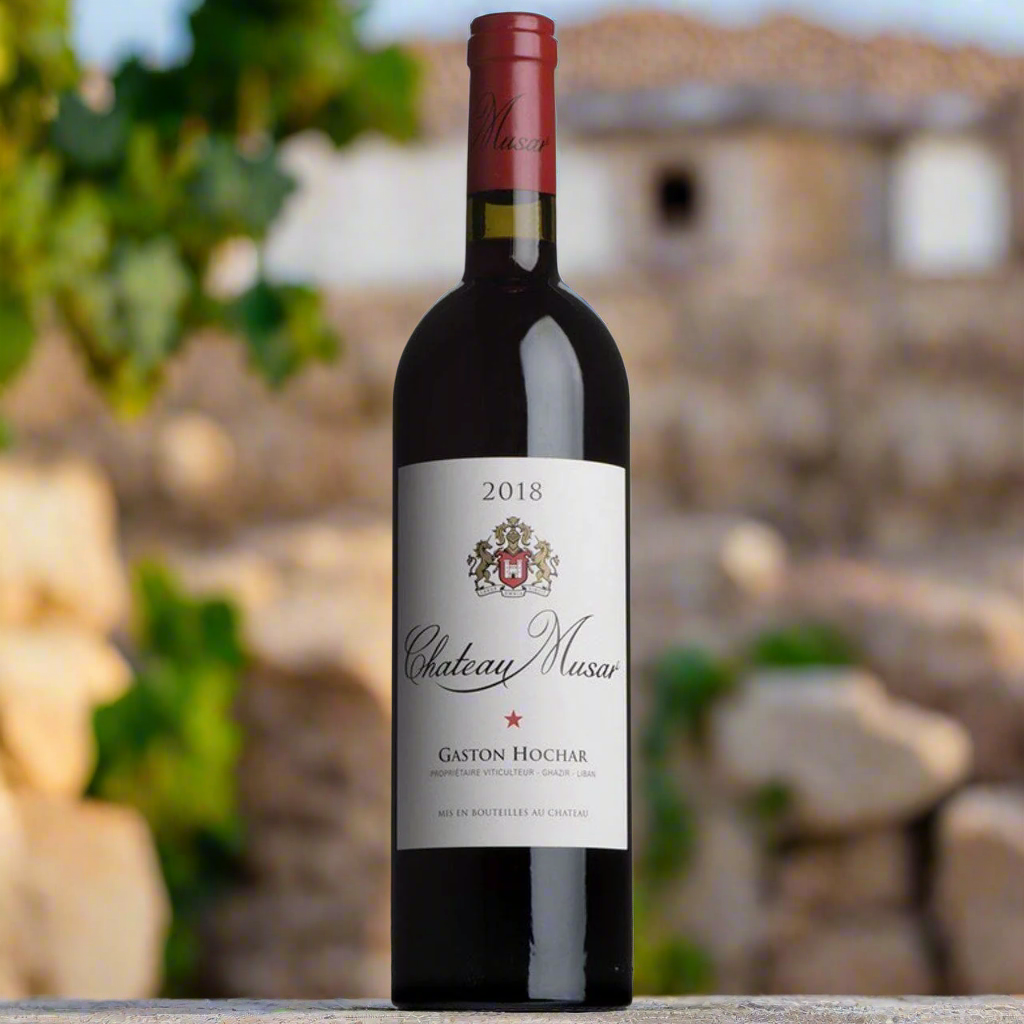Chateau Musar Red 2018 bottle on vineyard stone wall, Bekaa Valley backdrop