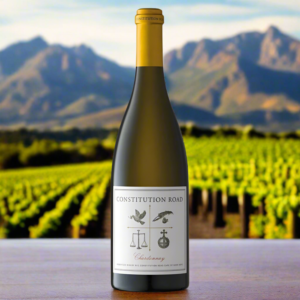 Place a bottle of Constitution Road Chardonnay on a wooden table with Cape mountain peaks and sunlit vines in the background, capturing a sense of place and scale.