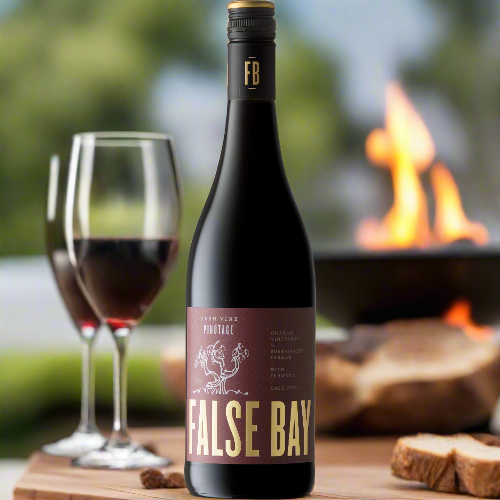 Outdoor table with a simple spread—grilled meats, firepit in the background, a couple of glasses of red wine.