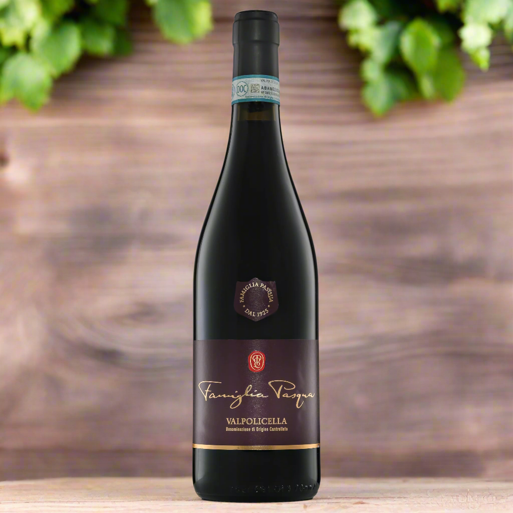 “Bottle of Famiglia Pasqua Valpolicella DOC on a rustic table with fresh cherries, herbs, and vineyard leaves. Soft natural light, classic Italian backdrop.”