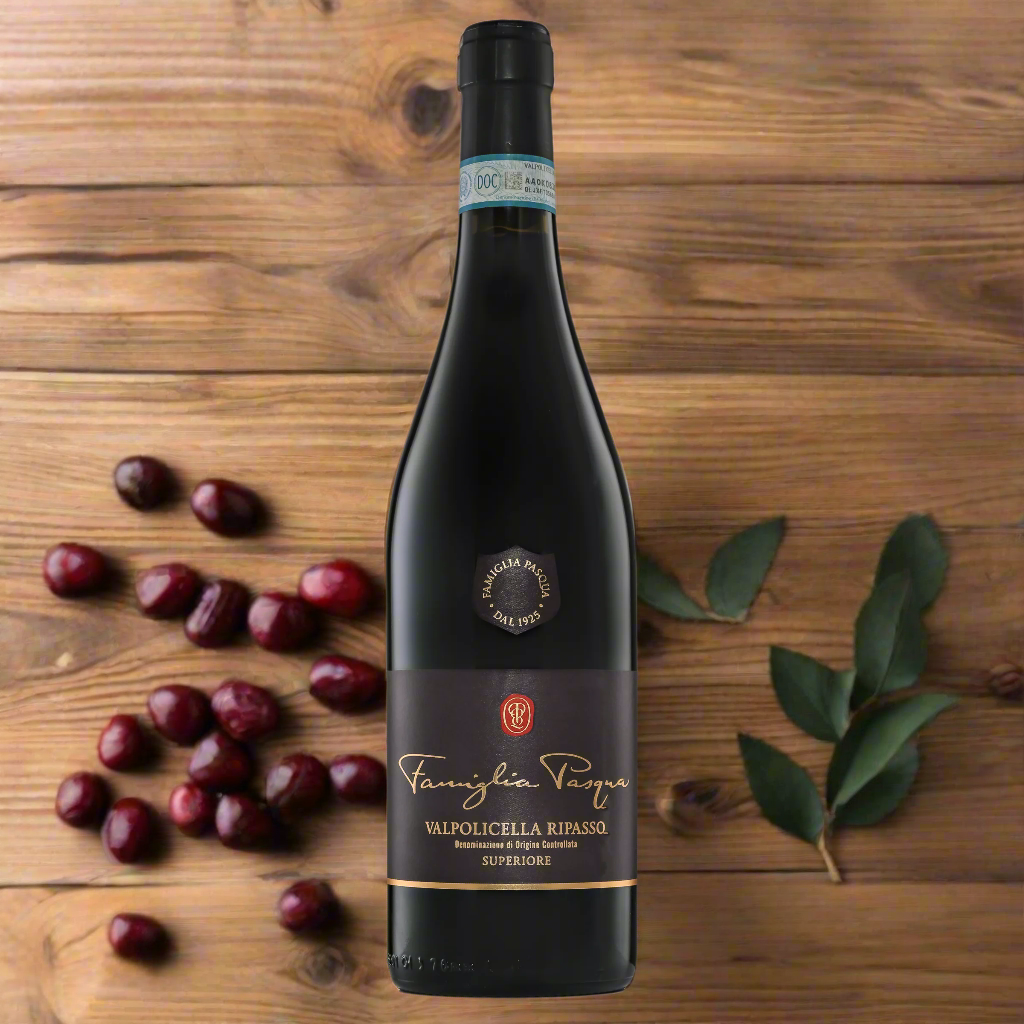 “Bottle of Famiglia Pasqua Valpolicella Superiore Ripasso on a rustic wooden table with dried cherries, bay leaves, and cracked black pepper. Warm lighting, classic Italian setting.”