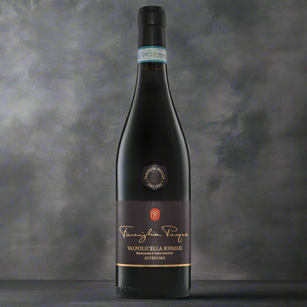 “Famiglia Pasqua Valpolicella Superiore Ripasso bottle on a dark stone surface with dried fruit, spice, and fresh herbs. Moody, minimalist background with contemporary styling.”
