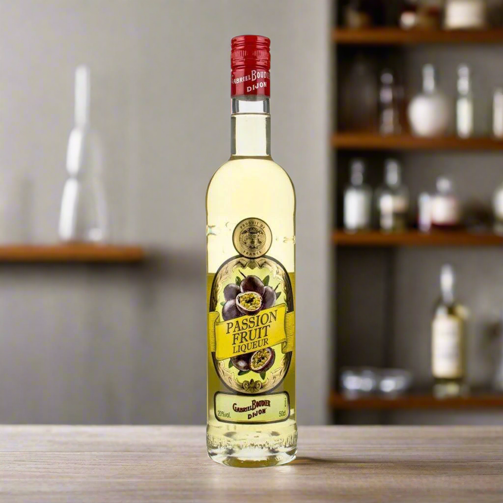 Gabriel Boudier Passion Fruit Liqueur on wooden bar counter with warm bottle shelf background.
