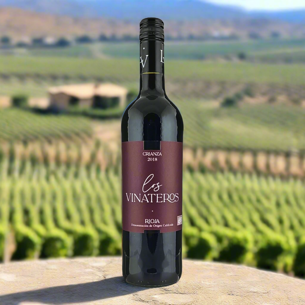 Los Vinateros Rioja Crianza bottle with vineyard and rustic background