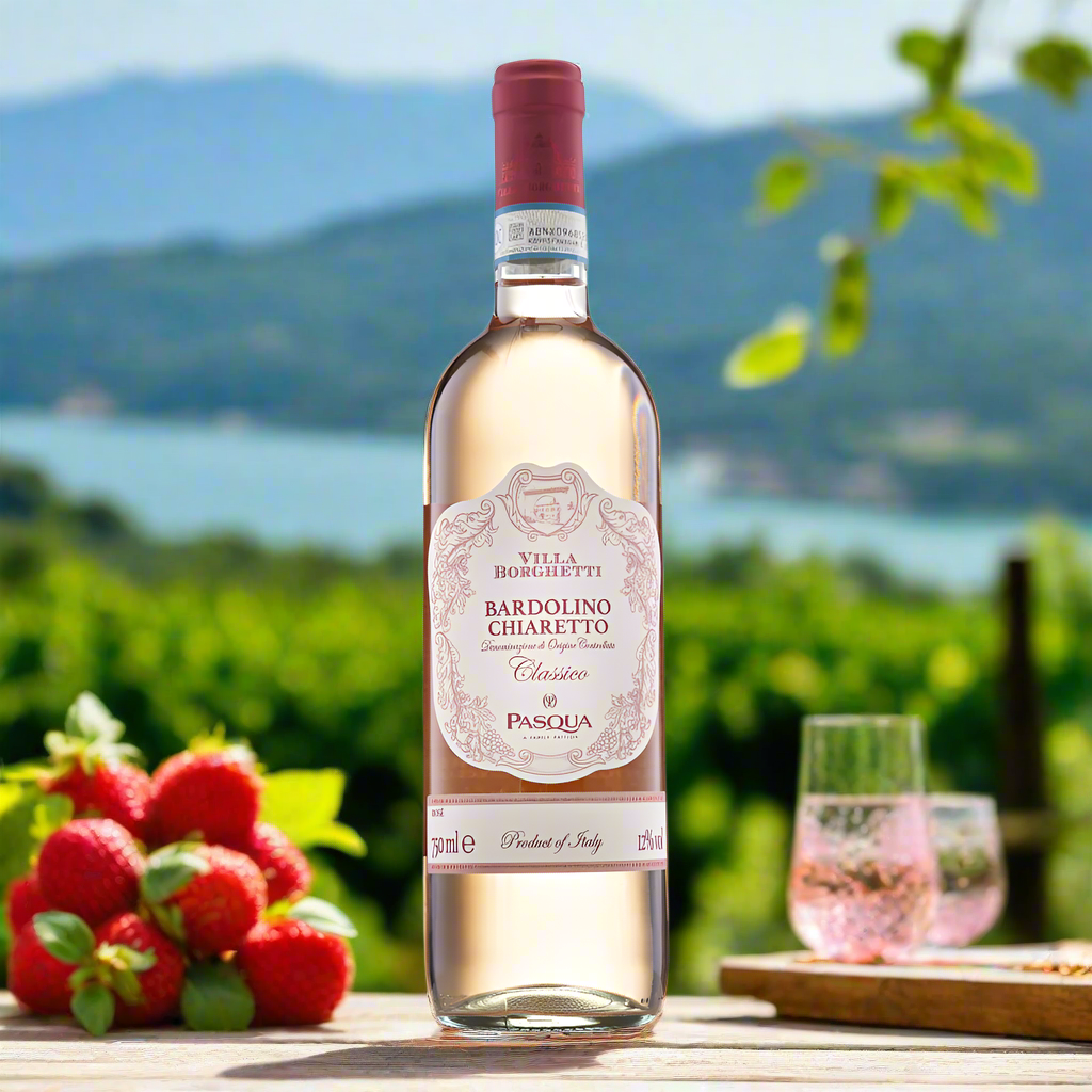 Bottle of Bardolino Chiaretto Rosé on a vineyard terrace with Strawberries and Lake Garda hills.