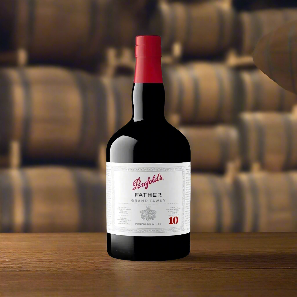 A dimly lit, atmospheric wine cellar with stacked oak barrels, aged wooden beams, and a vintage wooden table. On the table sits a refined bottle of tawny port with a half-filled glass, catching the soft amber glow of warm ambient lighting. The scene evokes heritage, craftsmanship, and quiet luxury.