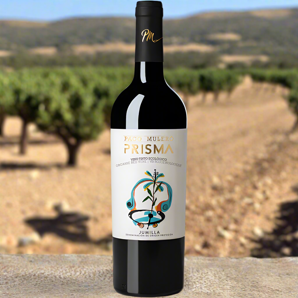 Place a bottle of Prisma Monastrell on a rustic stone table with dry, sunbaked hills and olive trees in the background, evoking the Jumilla region.