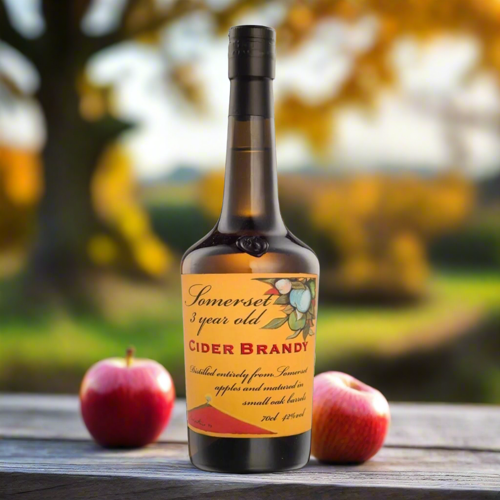 Somerset orchard in autumn, rustic table, bottle of cider brandy, tumbler glass, red apples, oak barrel, soft golden light.