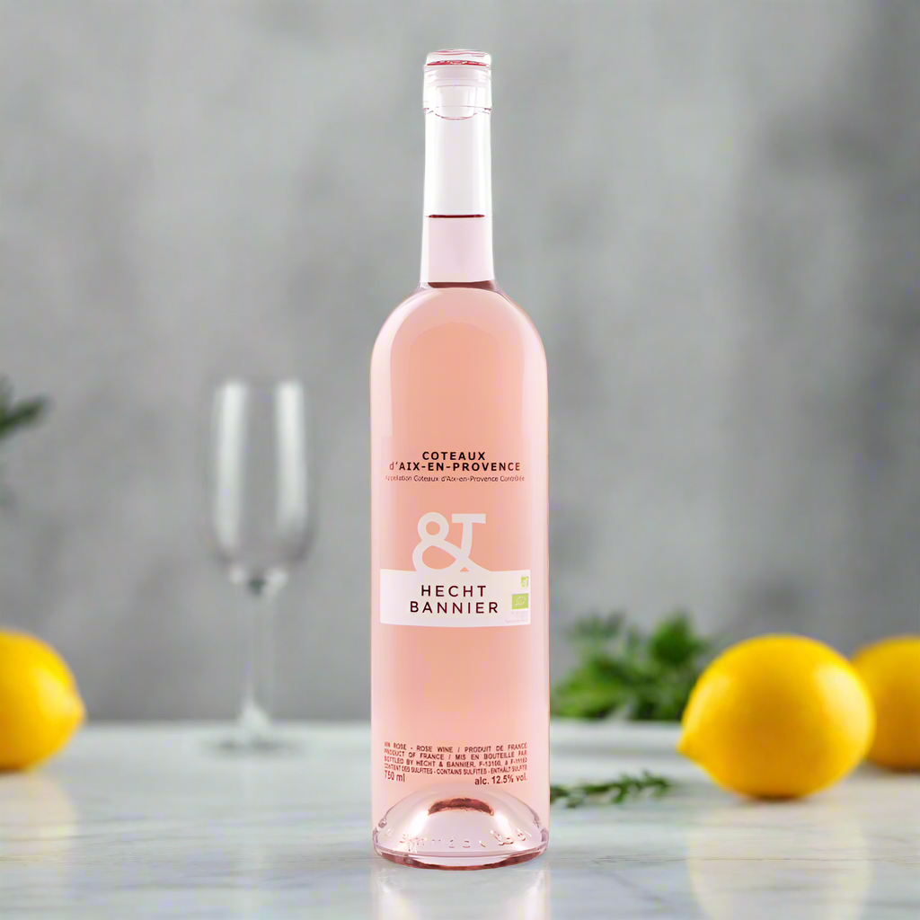 Hecht & Bannier Rosé bottle on marble counter with lemons, olives, and herbs in bright kitchen.