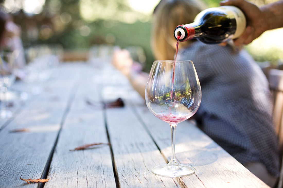 Red wine being poured into a glass at an outdoor summer table