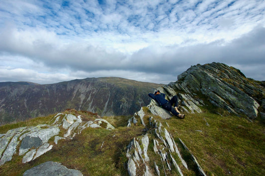 Hiker resting on a rocky mountain ridge under blue sky