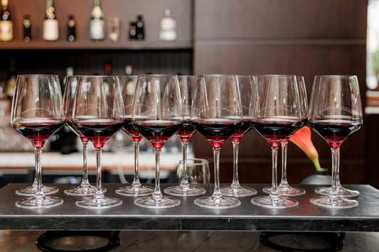 Row of red wine glasses lined up at a tasting bar
