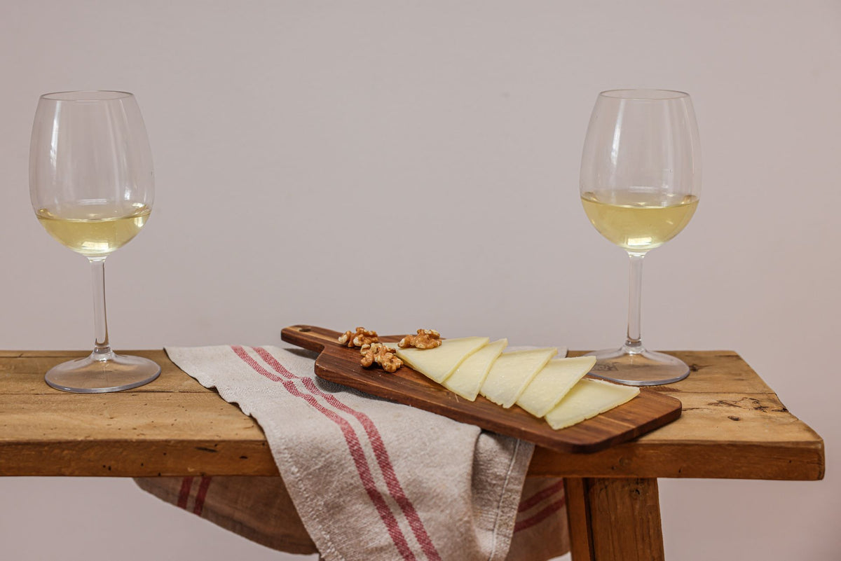 Cheese board with grapes and white wine glasses