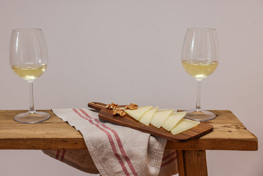 Cheese board with grapes and white wine glasses