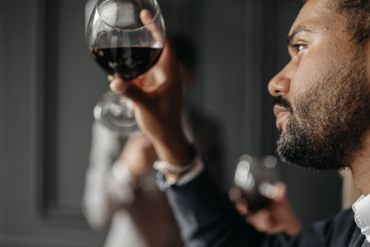 Man examining and nosing a red wine glass