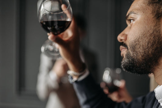 Man examining and nosing a red wine glass