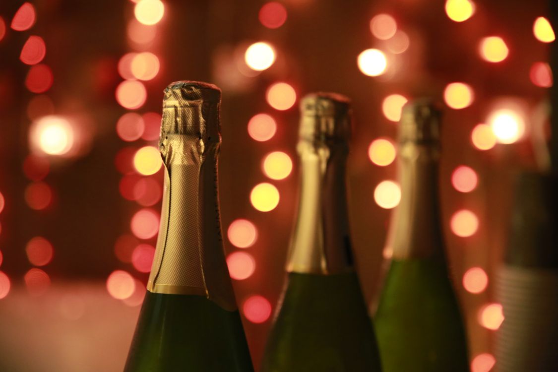 Four sparkling wine bottles with warm bokeh lights