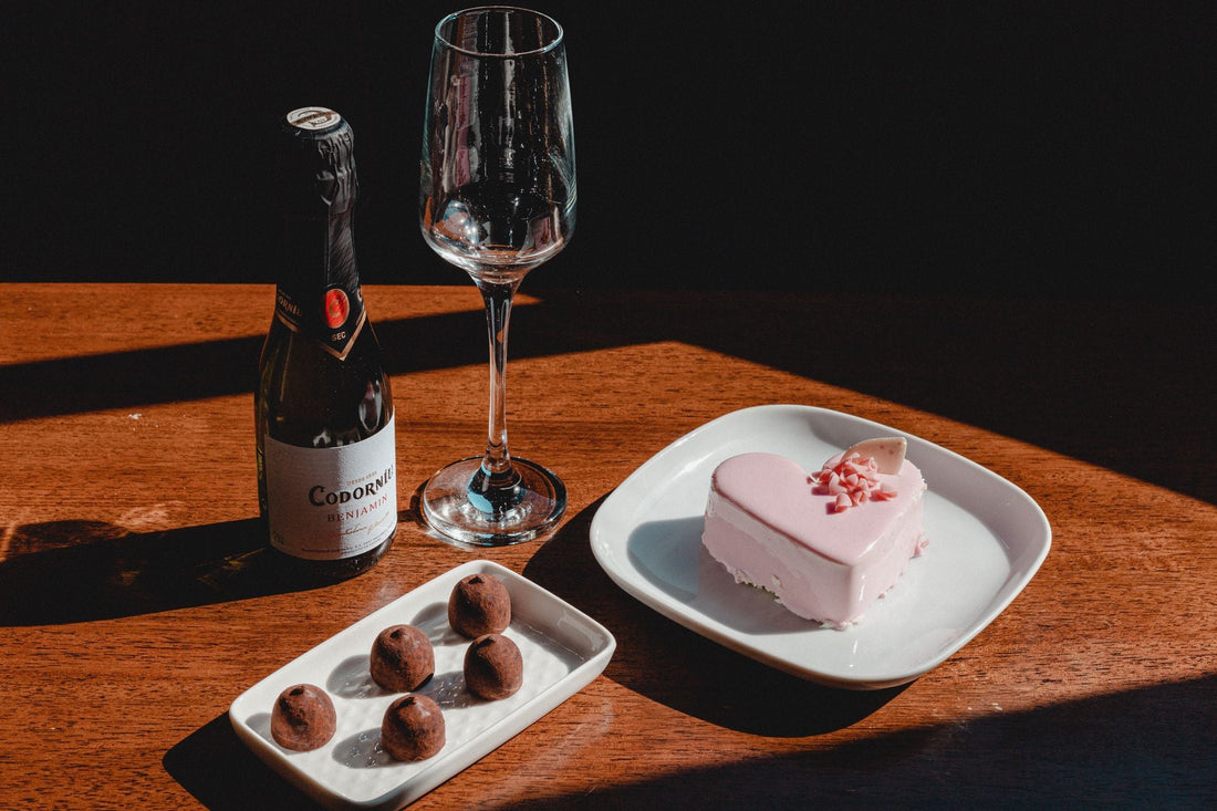 Wine glass and dark chocolates on a rustic wooden table with soft candlelight