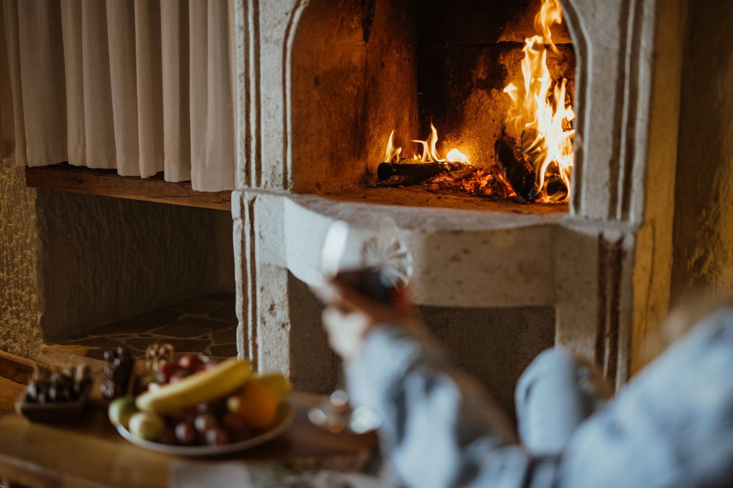 Glowing stone fireplace with fruit platter and wine glass creating a cosy Boxing Day celebration atmosphere