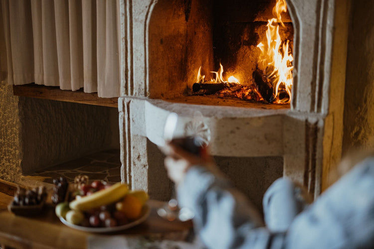 Glowing stone fireplace with fruit platter and wine glass creating a cosy Boxing Day celebration atmosphere