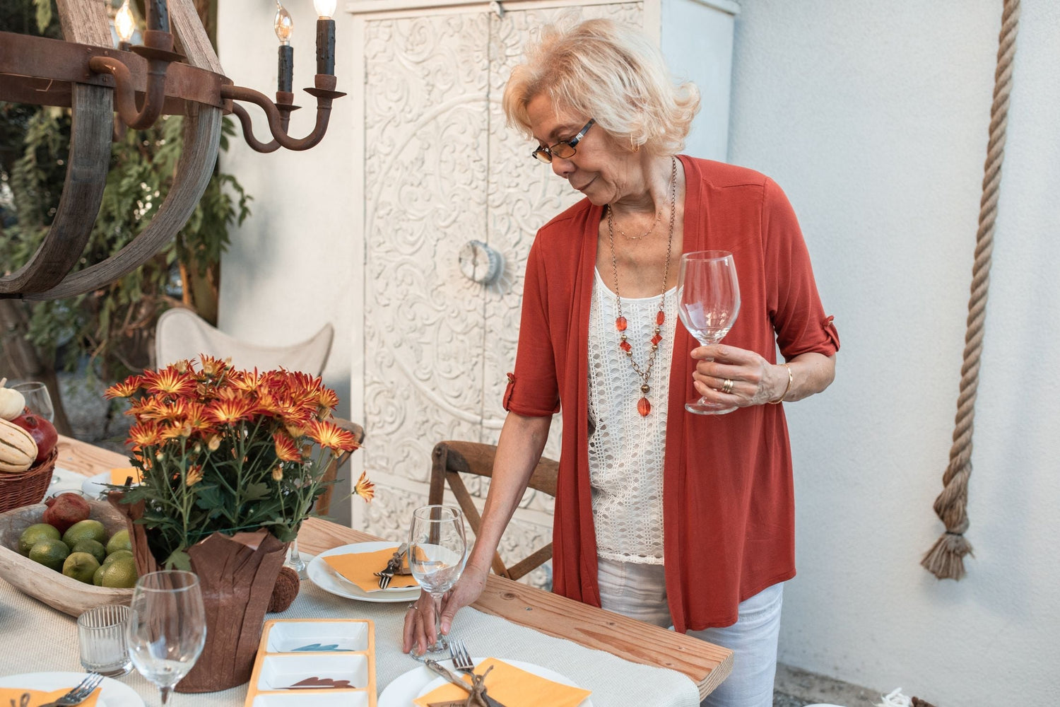 Woman in a red cardigan setting an outdoor table with a glass of red wine, brilliant value reds under £10