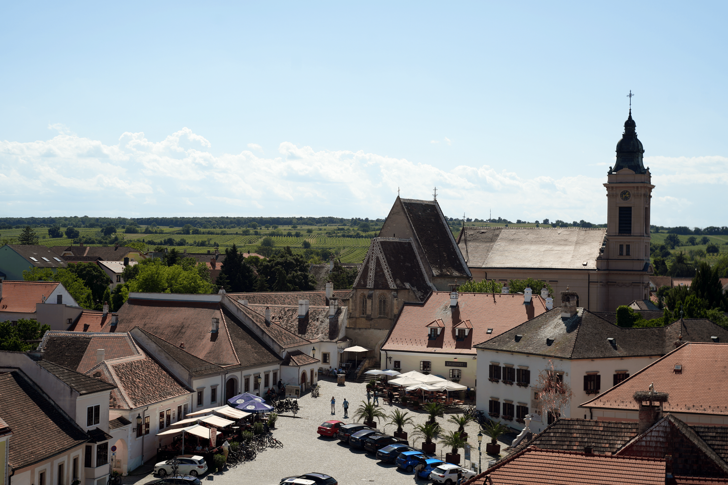 Traditional Austrian wine town with church tower, outdoor café terrace and hillside vineyards in the background, Burgenland, Austria
