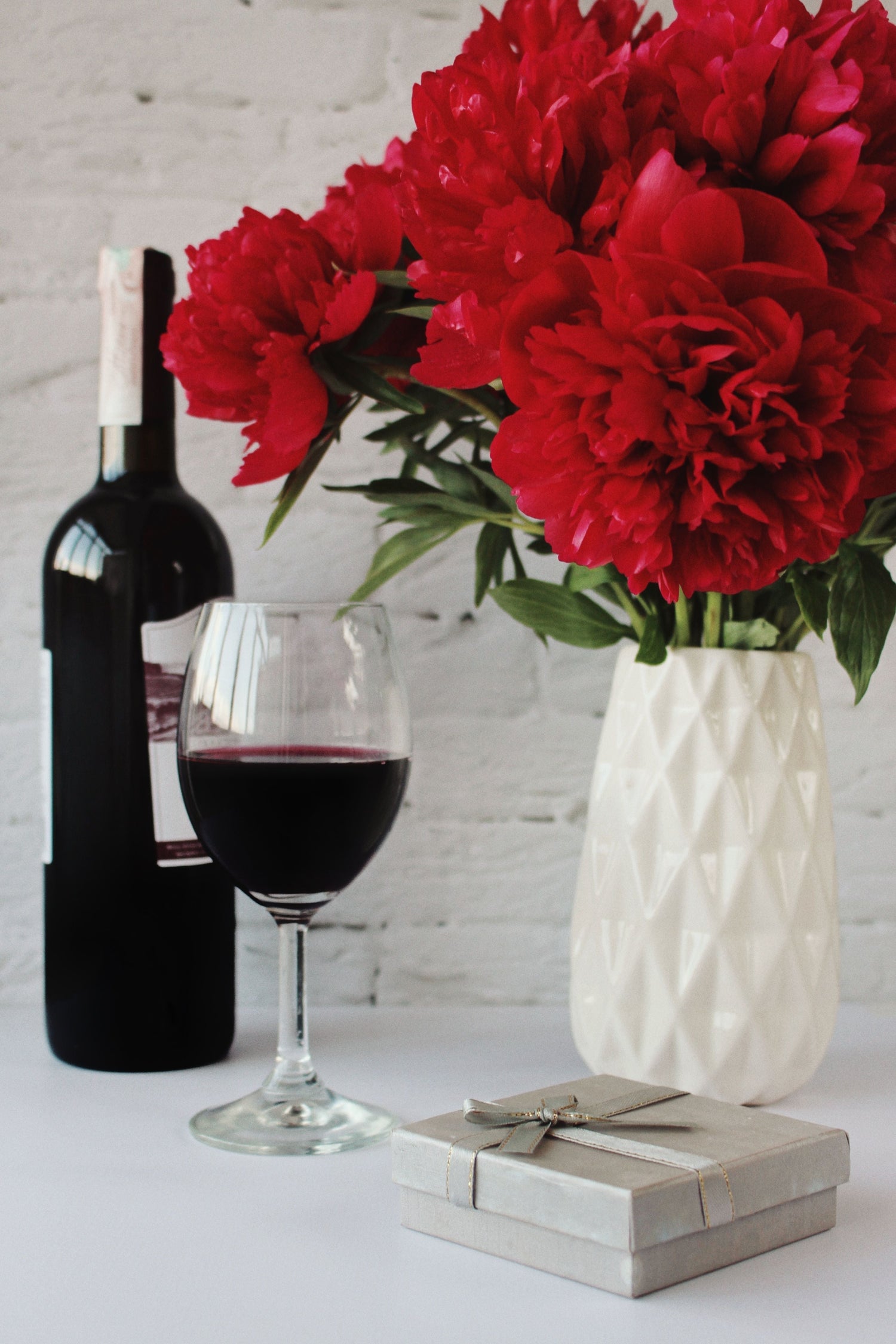 Wine bottle and gift box with red peonies.