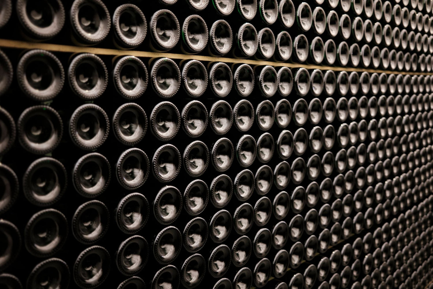 Hundreds of wine bottles stacked base-forward in a wine cellar, Brussels, Belgium — wine gifts under £200.