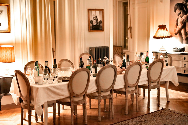 Long banquet table set with wine bottles and elegant oval-backed chairs, ready for a formal dinner with magnum-format wines