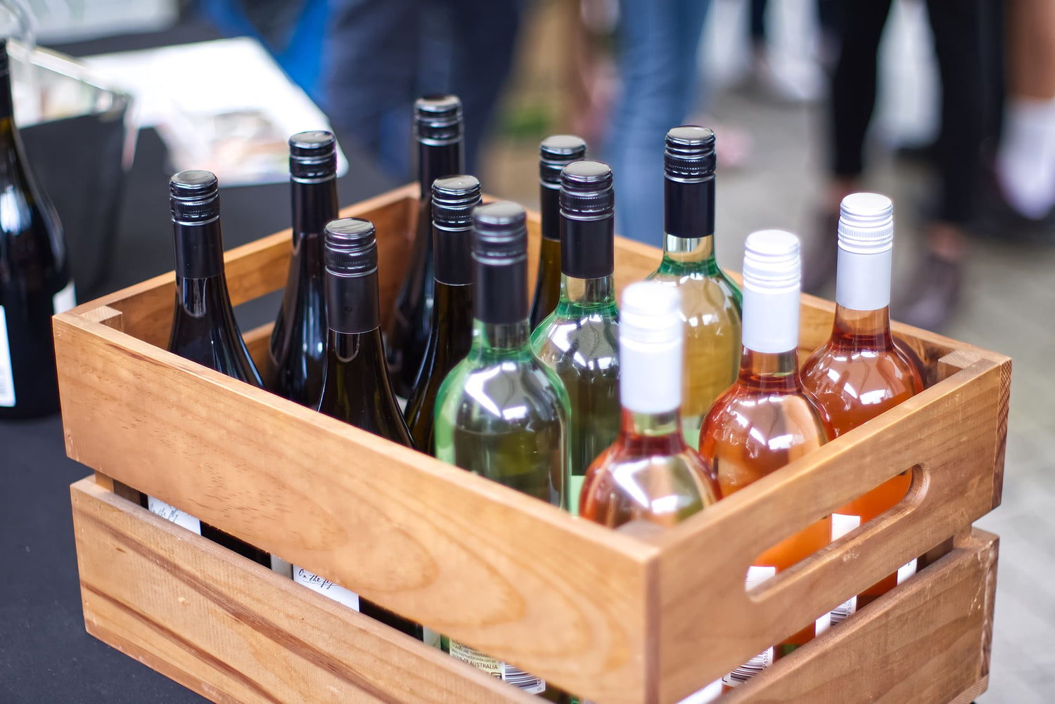A wooden wine case filled with a mixed selection of red, white and rosé bottles, ready for a mixed-case delivery