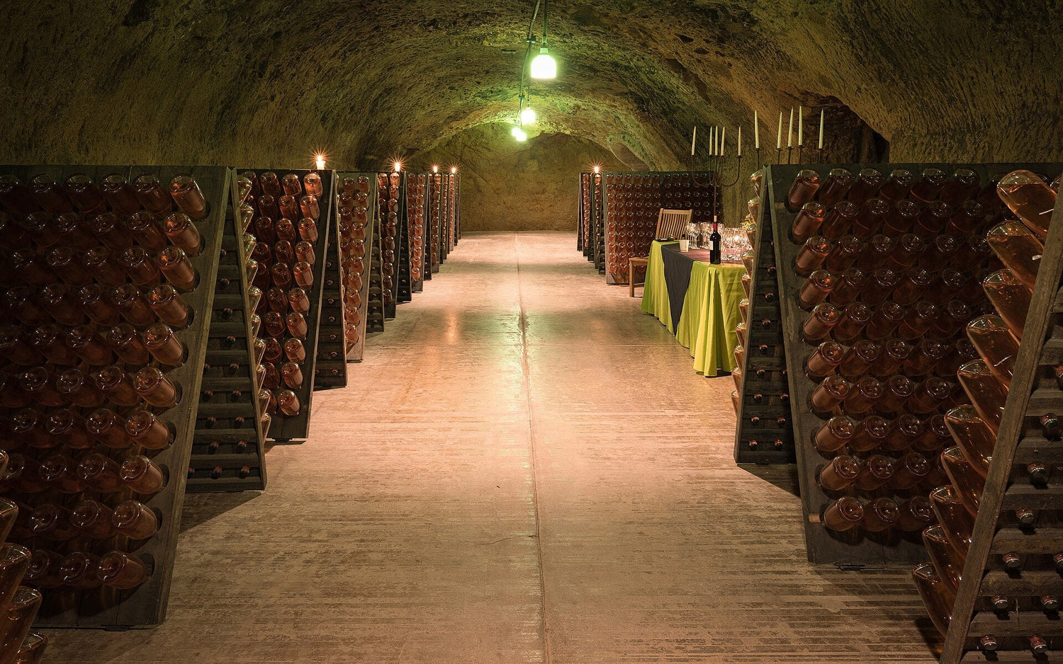 Stone-vaulted wine cave with riddling racks of sparkling wine bottles and a tasting table at the far end, Out of America cellar. Photo: Frank Schulenburg (CC BY-SA 4.0)