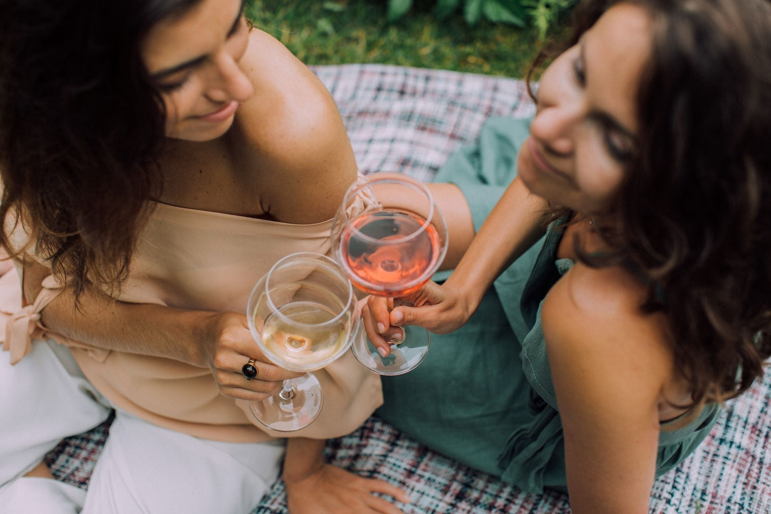 Two friends relaxing outdoors with glasses of rosé wine, celebrating the Pink and Rosé Collection