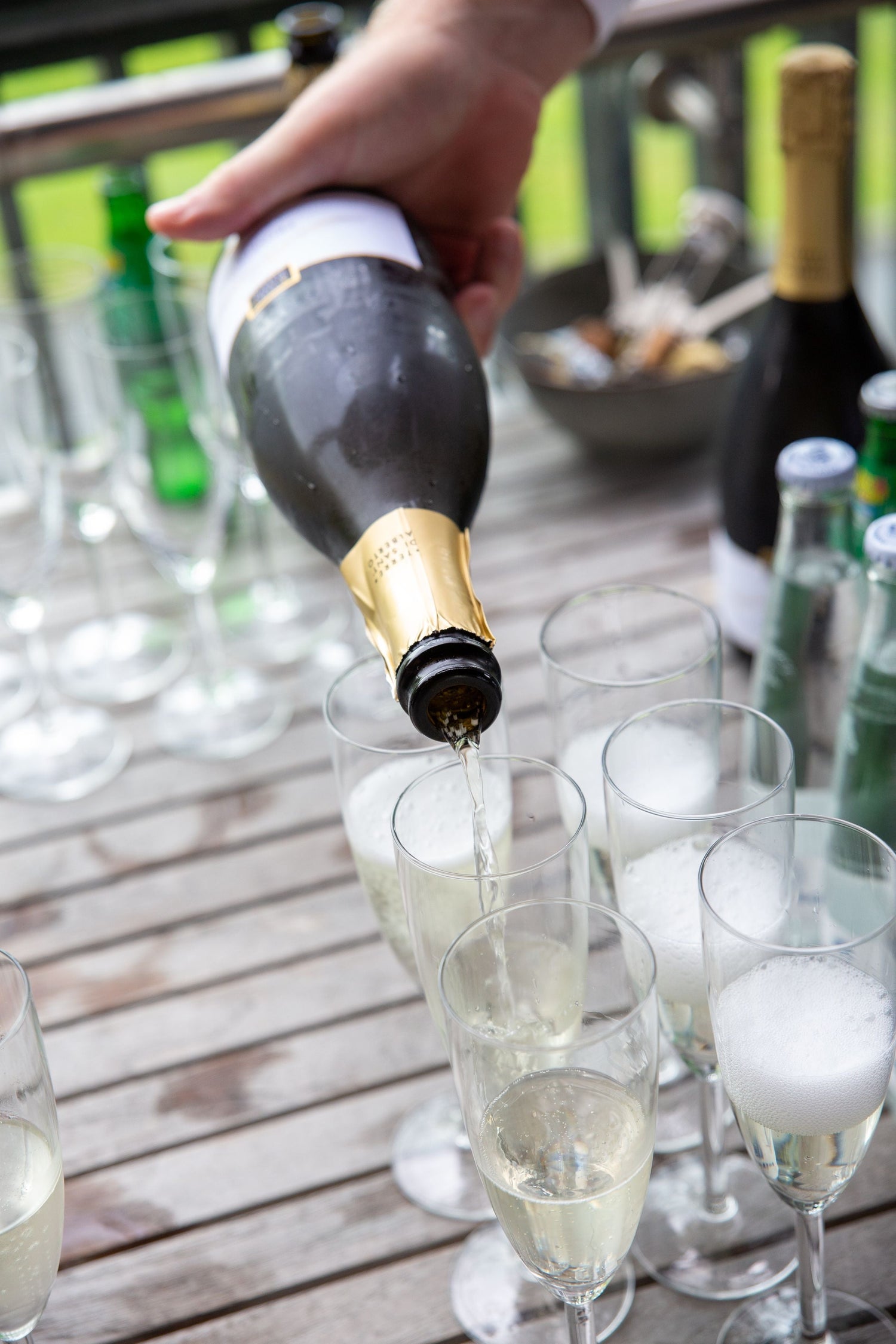 Sparkling Prosecco being poured into flutes at an outdoor garden party celebration