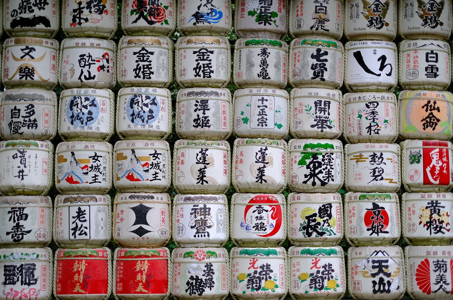 Traditional Japanese kazaridaru sake barrels stacked at a Shinto shrine, decorated with kanji calligraphy and colourful designs