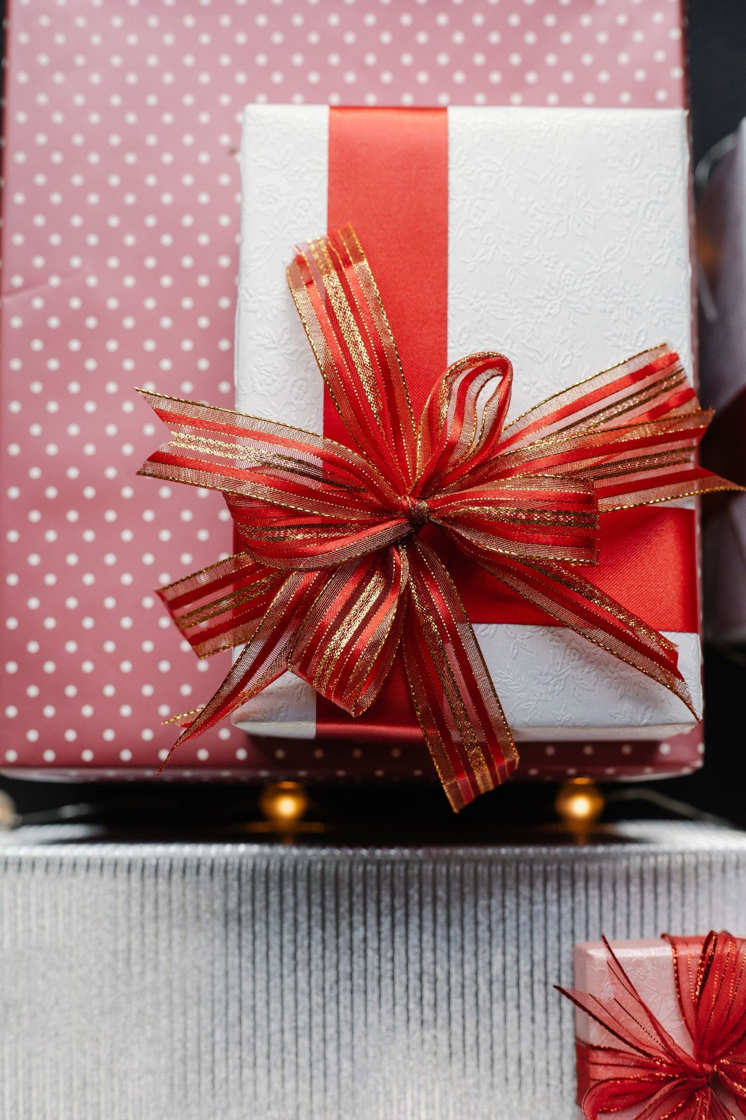 Elegant white and pink gift boxes tied with red and gold ribbons and bows — perfect thank you wine gifts