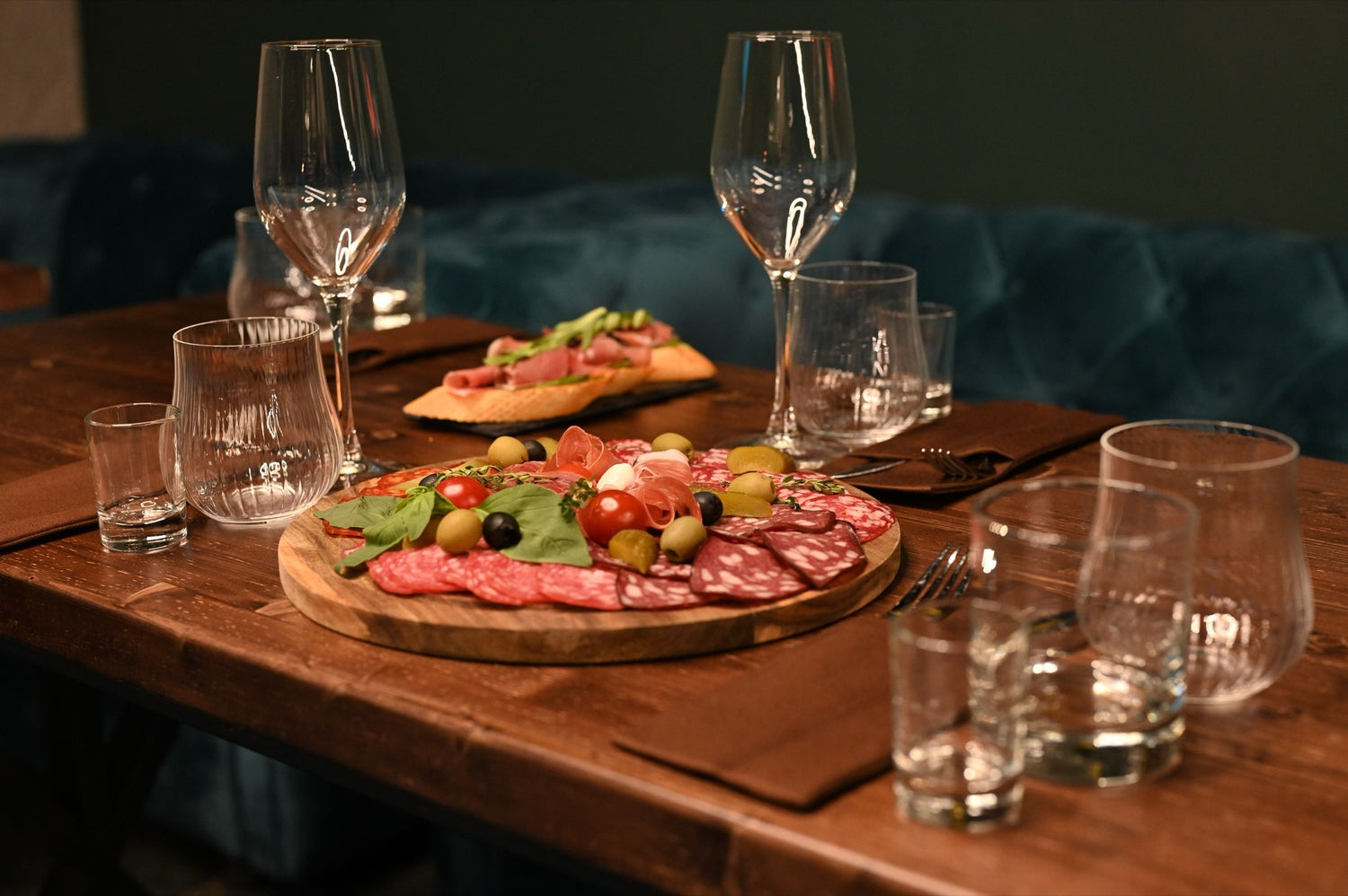 Charcuterie board with salami, olives, cherry tomatoes and mozzarella on a restaurant table set with wine glasses, gourmet wine and food sale