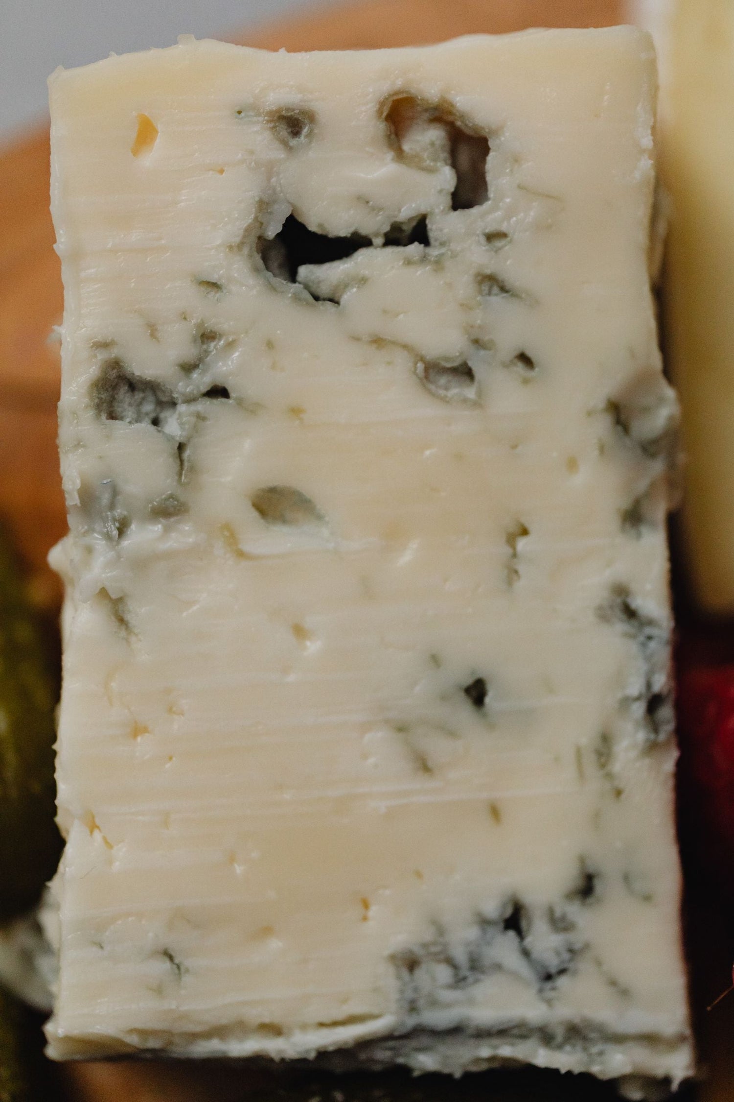 Close-up of a creamy wedge of blue-veined cheese with visible mould pockets — perfect pairing choice for blue cheese wines