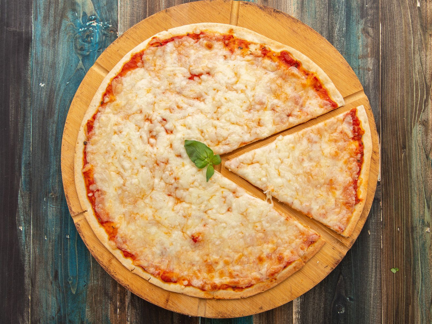 Classic Margherita pizza with melted mozzarella and a fresh basil leaf on a round wooden board — wine pairing for pizza