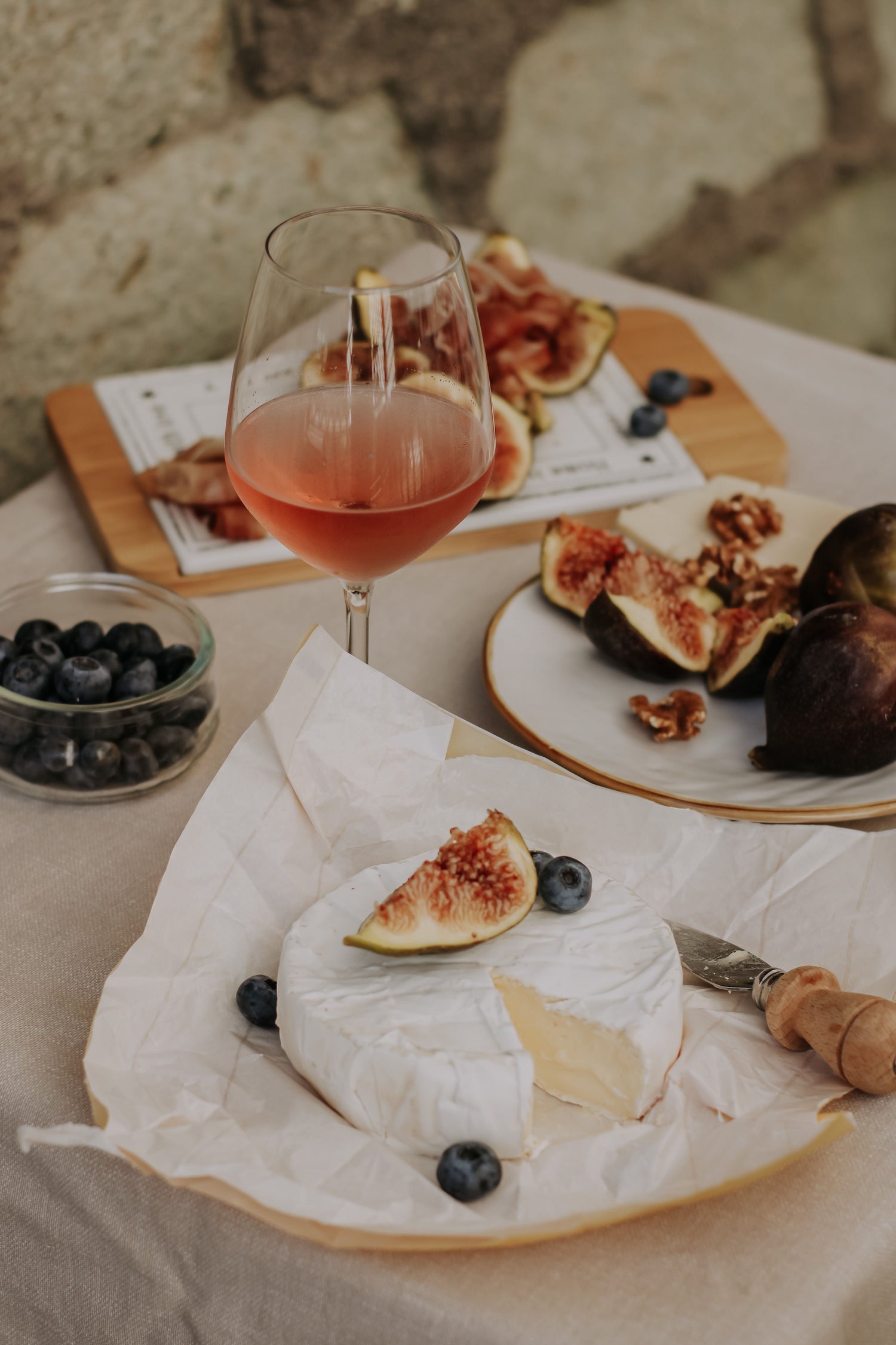 Camembert cheese with figs, blueberries and a glass of rosé wine.