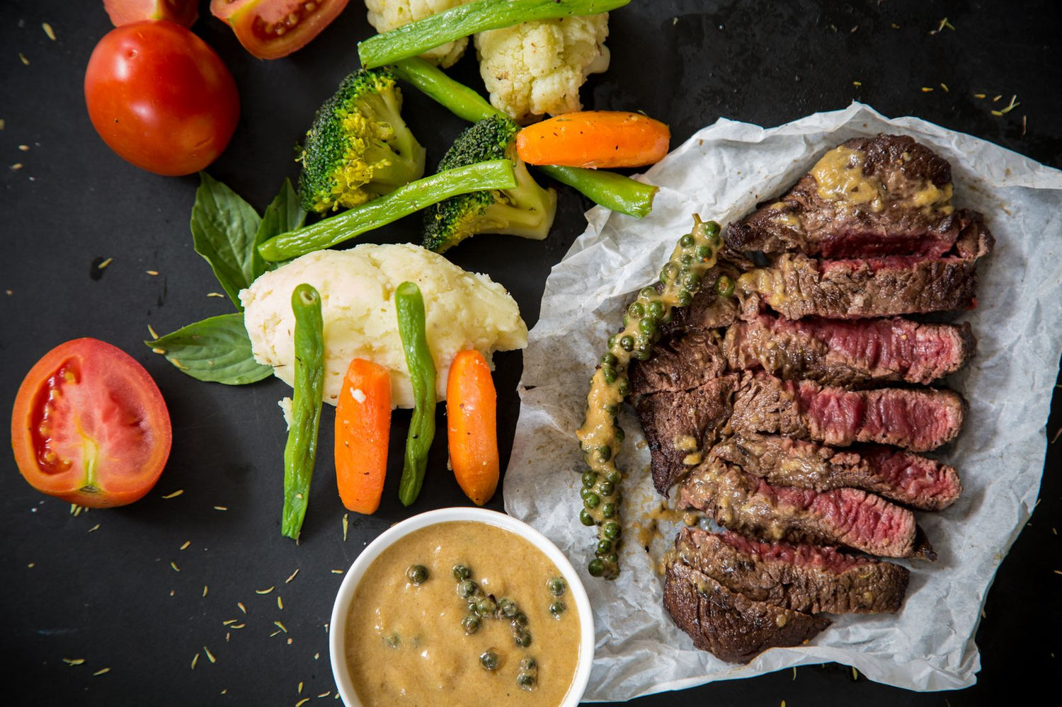 Sliced medium-rare steak with peppercorn sauce alongside mashed potato, broccoli, green beans and carrots — wine pairing for steak