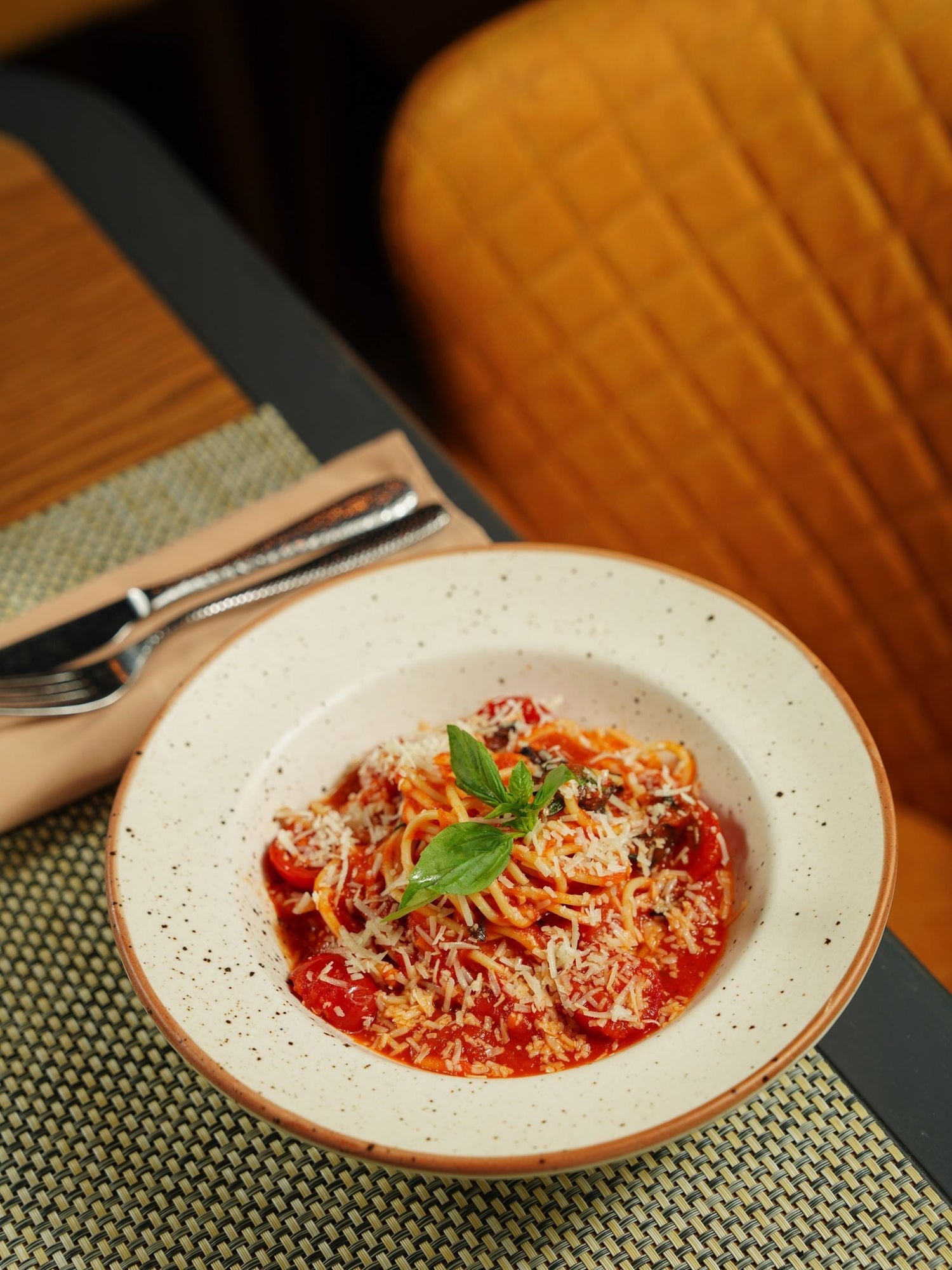 Spaghetti in rich tomato sauce with cherry tomatoes, fresh basil and grated cheese in a white ceramic bowl — wine pairing for tomato pasta