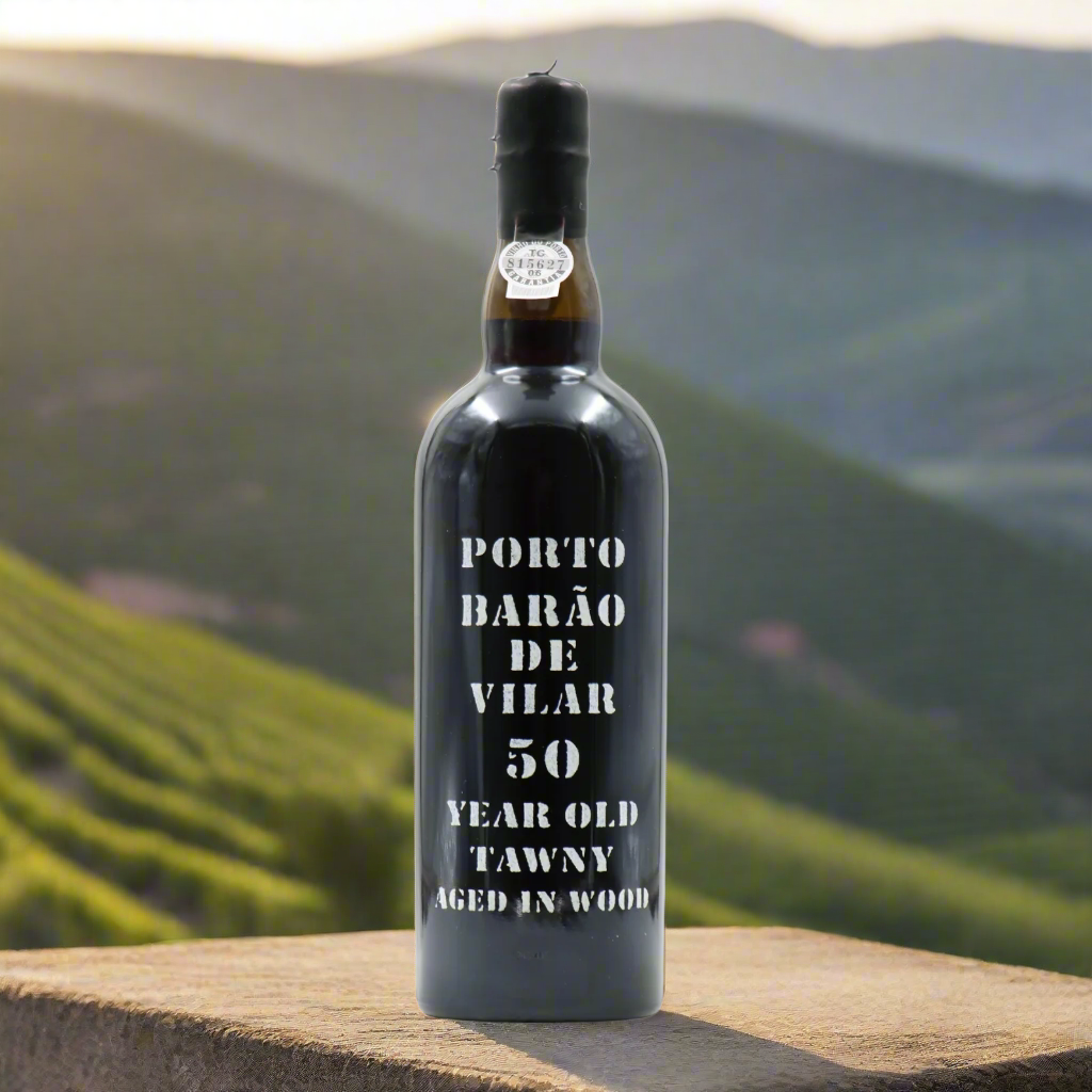 Barão de Vilar 50 Year Old Tawny Port bottle on a stone terrace overlooking the Douro Valley at sunset.