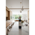 Chateau La Patache Pomerol wine bottle displayed on a polished stone dining table in a bright contemporary kitchen and entertaining space.