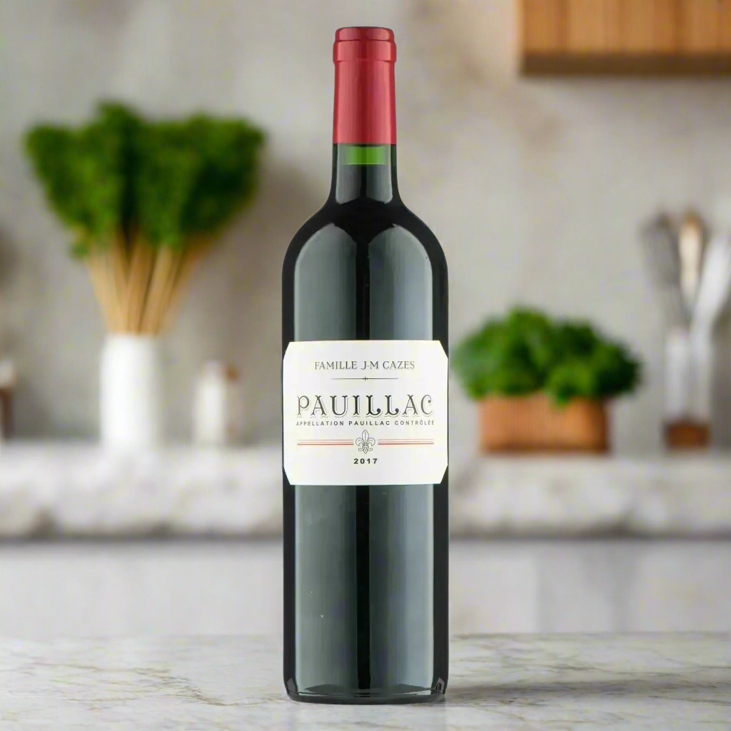 Famille JM Cazes Pauillac 2019 on modern kitchen counter with herbs and rustic breadboard