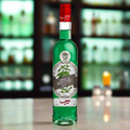 Green bottle with red cap on a bar counter with blurred shelves in the background
