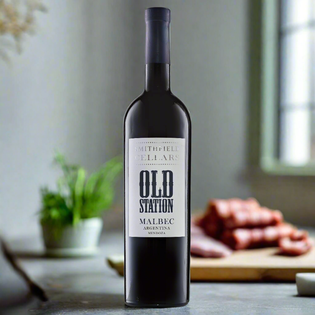 Old Station Malbec bottle on modern kitchen counter with chorizo and herbs