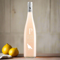 Bottle of Picpoul Rosé wine with two lemons on a wooden surface.